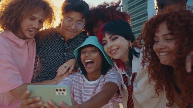 Diverse young friends capturing shared moments, laughing and taking group selfies with smartphones during golden sunset in vibrant urban cityscape