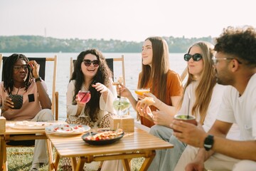 Friends enjoying drinks and food by the lake