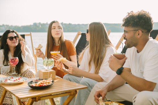 Friends enjoying drinks and food by the lake