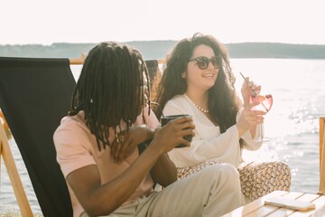 Friends enjoying drinks by the lake at sunset