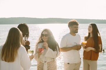 Friends enjoying drinks by the lake at sunset