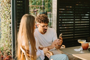Friends looking at smartphone and relaxing at the cafe