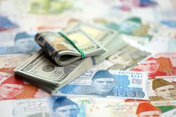 Bunch of US dollar bills lies on big amount of Pakistan rupees banknotes close up