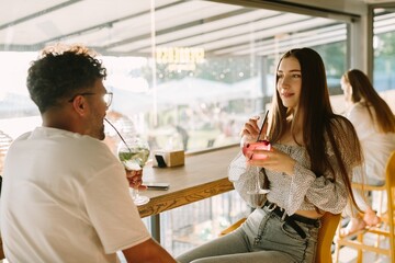 Friends enjoying cocktails in a modern cafe, talking and laughing