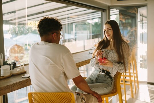 Young couple enjoying drinks and conversation in a cafe - Powered by Adobe