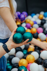 Hand Holding Green Balls in Colorful Ball Pit