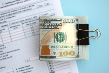 Big amount of United States dollar bills on table with tax return form close up