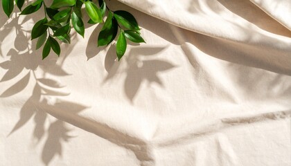 Minimalist abstract background of a soft green leaf shadow on a textured, neutral beige linen fabric.

