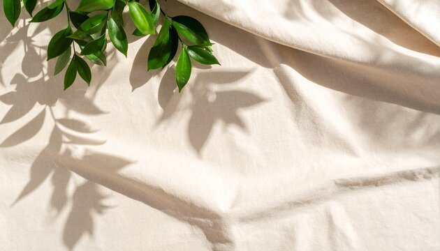 Minimalist abstract background of a soft green leaf shadow on a textured, neutral beige linen fabric.


