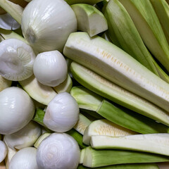 Fresh sliced zucchini and peeled onions prepared together for cooking or home preservation,...