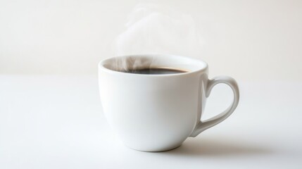 Obraz premium White cup of steaming black coffee on white surface