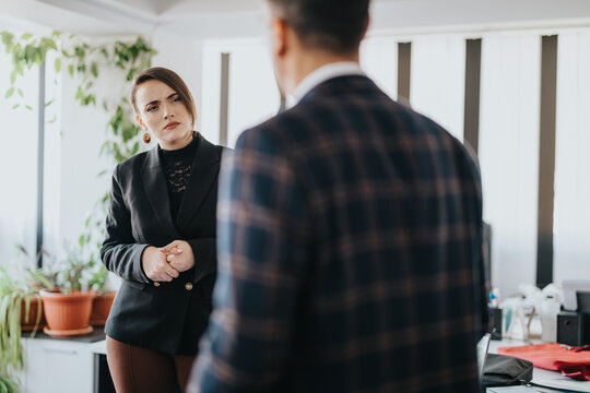 Two business individuals are having an important conversation in a modern office setting. The interaction exudes professionalism and determination, captured amidst an environment accentuated with
