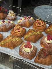 Danish pastry on a a cafe showcase behind the window: view from the street. Tasty buns and...