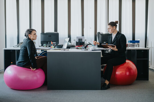 A modern office scene with colleagues using fitness balls as seating while working