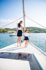 Mother and daughter spending time together on the bow of a sailing yacht. Family bonding, sea...