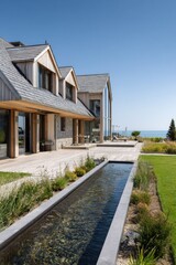 This stunning modern coastal home boasts a spacious patio and a tranquil water feature, all while offering breathtaking views of the ocean on a clear, sunny day