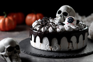 Spooky Halloween chocolate Cake with Skull, Eyeball, and Spider Decoration on dark background