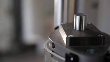 Close-up of a universal testing machine applying pressure on a metal cylinder in a quality control laboratory