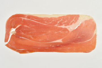 A studio shot, close-up, top-down view on a neutral background features a single, thinly sliced piece of prosciutto, showcasing its distinct marbled texture