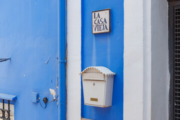 A vintage mailbox and a sign reading 'La Casa Vieja' on a bright blue wall, creating a charming, colorful scene in Alicante, Spain, reflecting local architecture.