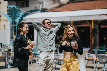 Three young adults share laughter and well-crafted beverages at a vibrant outdoor location,...