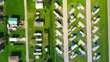Port Bolivar Texas beachside aerial showing RVs parked on concrete pads and grass beside stilt homes. Coastal textures and modular vacation setup highlight beachfront living area near Galveston