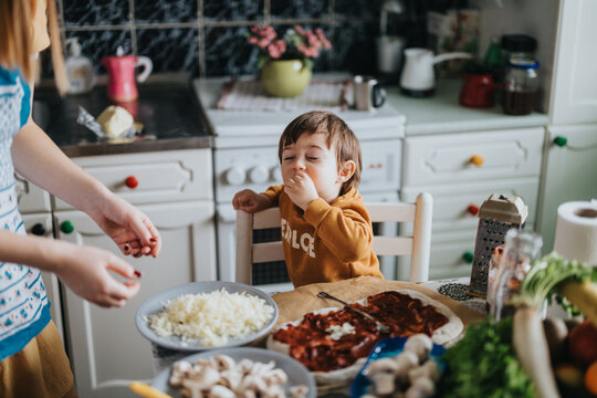 A joyful moment of a parent and toddler cooking together, highlighting warmth, family bonding, and the enjoyment of preparing meals in a homely environment with fresh ingredients.