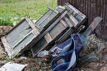 Discarded wooden windows and a blue backpack create an intriguing contrast in a natural setting