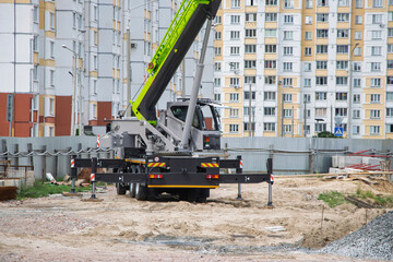 Construction crane at urban site working on new development project surrounded by residential...
