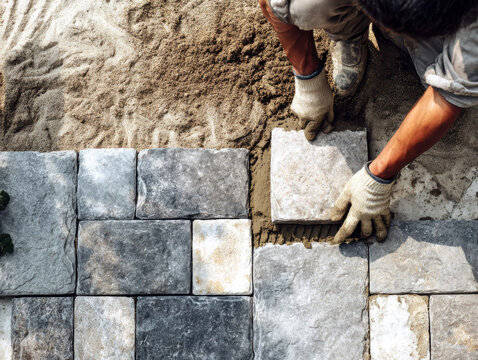 Construction Worker Laying Stone Pavers in a Sand Bed for a Patio or Walkway