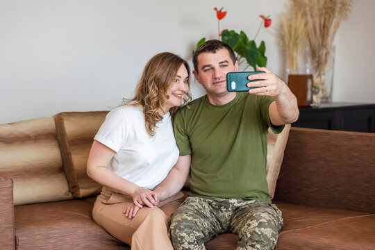 Military Soldier at Home.  Happy Military Man with his Wife Taking Photo Selfie Resting Relaxing Indoor. Military Rotation concept.
