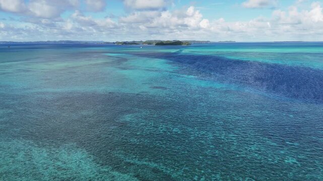 Dynamic drone shot sweeping across the electric-blue seas and untouched islands of Palau. wide cinematic drone shot.