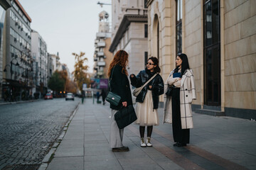 A group of three women engaged in an animated discussion on a city sidewalk, surrounded by urban...