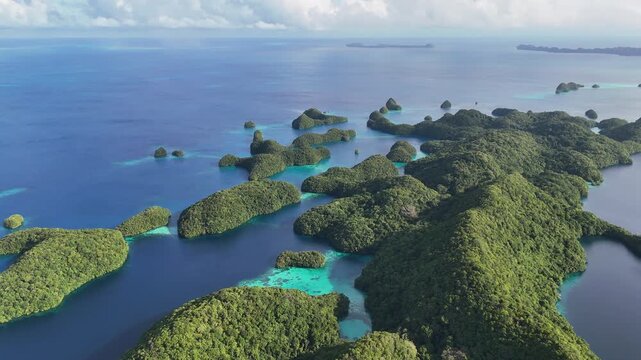 High-quality drone shot hovering and revealing the crystal blue waters and islands of Palau. Panning wide drone shot.