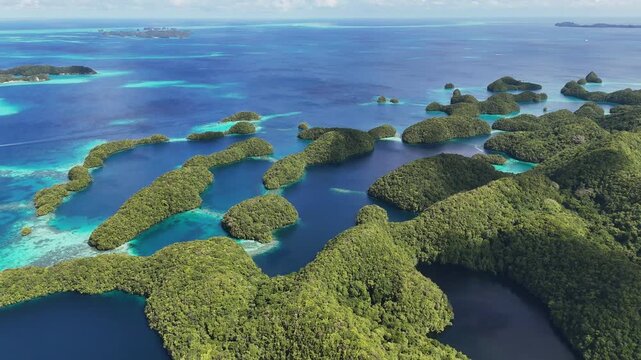 Breathtaking drone view panning and revealing the vivid aqua ocean and green-covered terrain around Palau. Wide cinematic drone shot