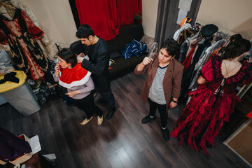 A group of young performers getting ready for a theatrical play, dressing in costumes and studying...