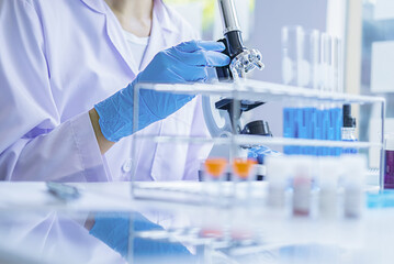 Scientist in blue gloves examining samples under a microscope in a laboratory