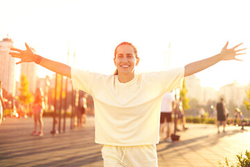 Happy runner breathing fresh air outstretching arms at sunset in the city