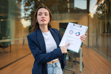 Businesswoman pointing at balance sheet, explaining financial report, showing diagrams and charts