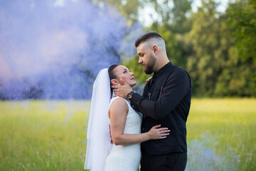 Bride embracing groom against a background of colored smoke. A soft, romantic moment in a creative...