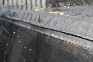 A blurred, close-up shot of raindrops splashing onto a dark, reflective surface, creating abstract...