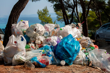 Garbage pile scattered near a roadside  in a forest setting. Toxic plastic into nature everywhere....