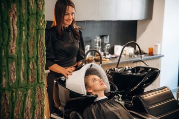 Using the LED hair growth helmet. Woman is in a beauty salon with hair stylist