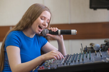 Young woman mixing live sound. Girl recording a song in the studio. 
