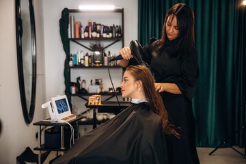 Drying the hair. Woman is in a beauty salon with hair stylist