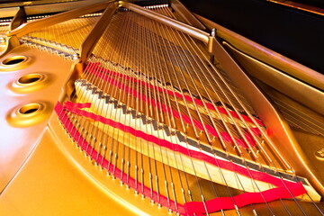 A horizontal photo of the strings and soundboard of a grand piano.