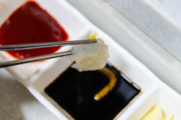 slice of puffer fish sashimi on the soy sauce