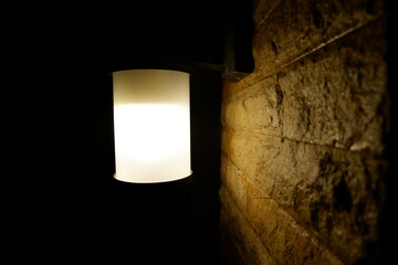 Illuminated Wall Lamp on Textured Brick Surface at Night