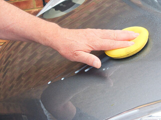 Close up of cleaning car body with clay for removing bonded surface contaminants that washing alone...