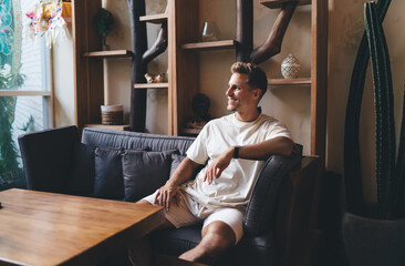 Freelancer sitting back on couch in relaxed posture, gazing with content expression, symbolizing...
